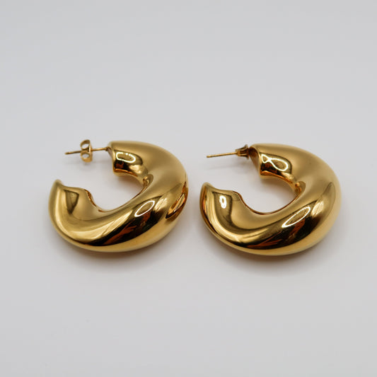 Pair of gold hoop earrings on a light gray background