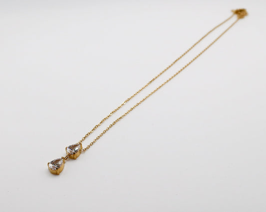 Gold necklace with teardrop-shaped pendants on a light gray background