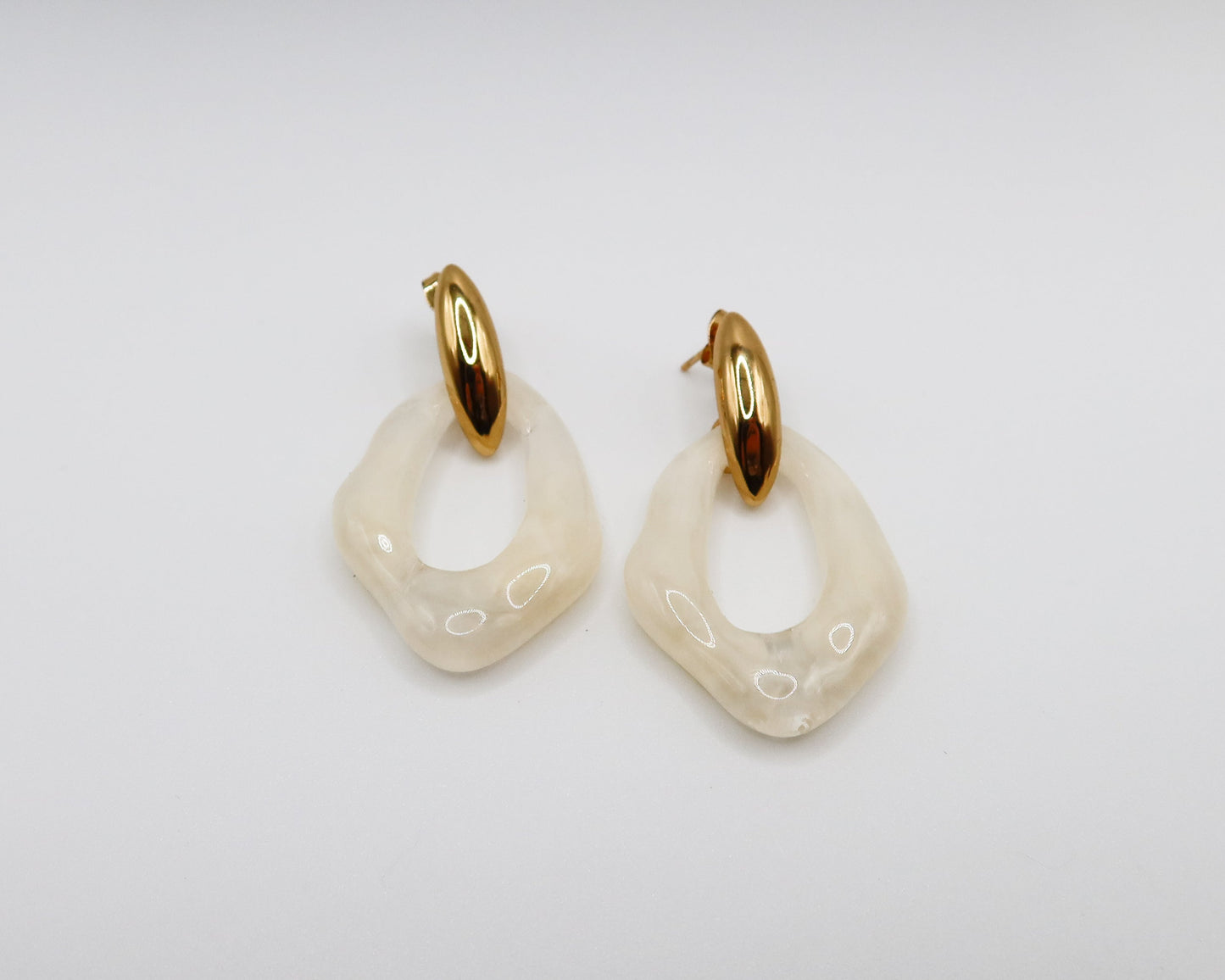 Pair of gold and white hoop earrings on a light gray background