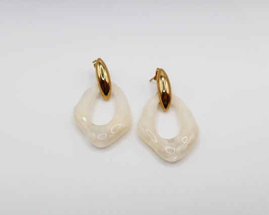 Pair of gold and white hoop earrings on a light gray background