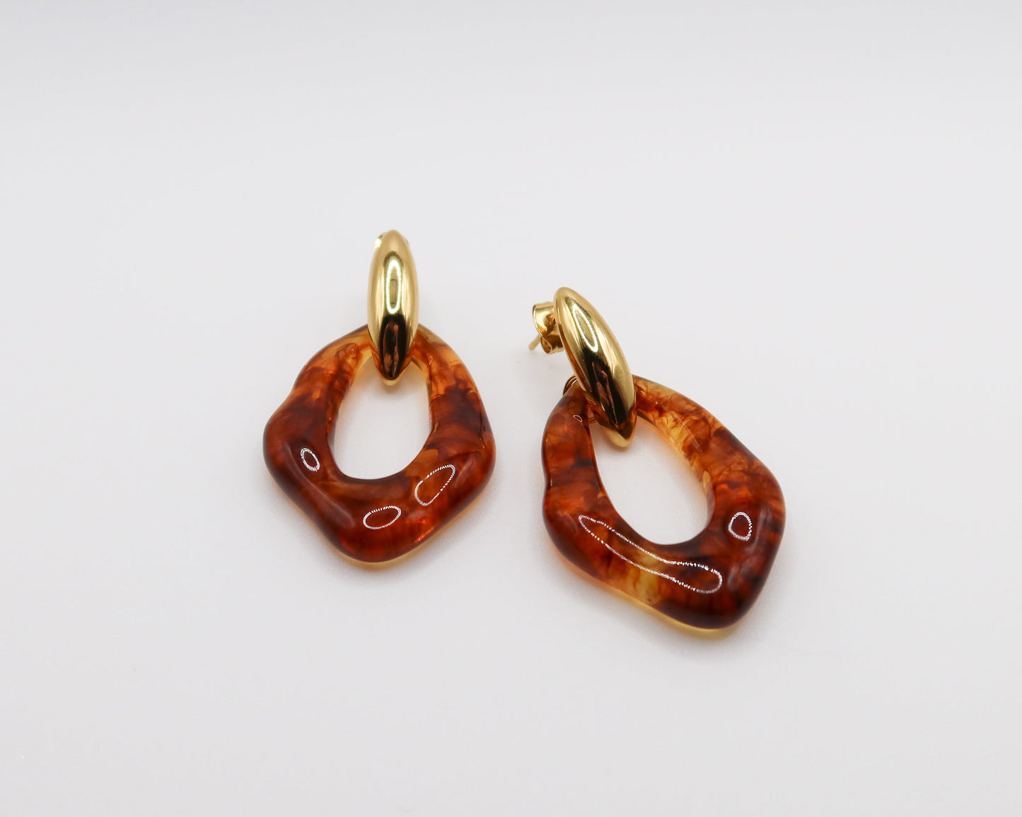 Pair of amber hoop earrings with gold hooks on a light gray background