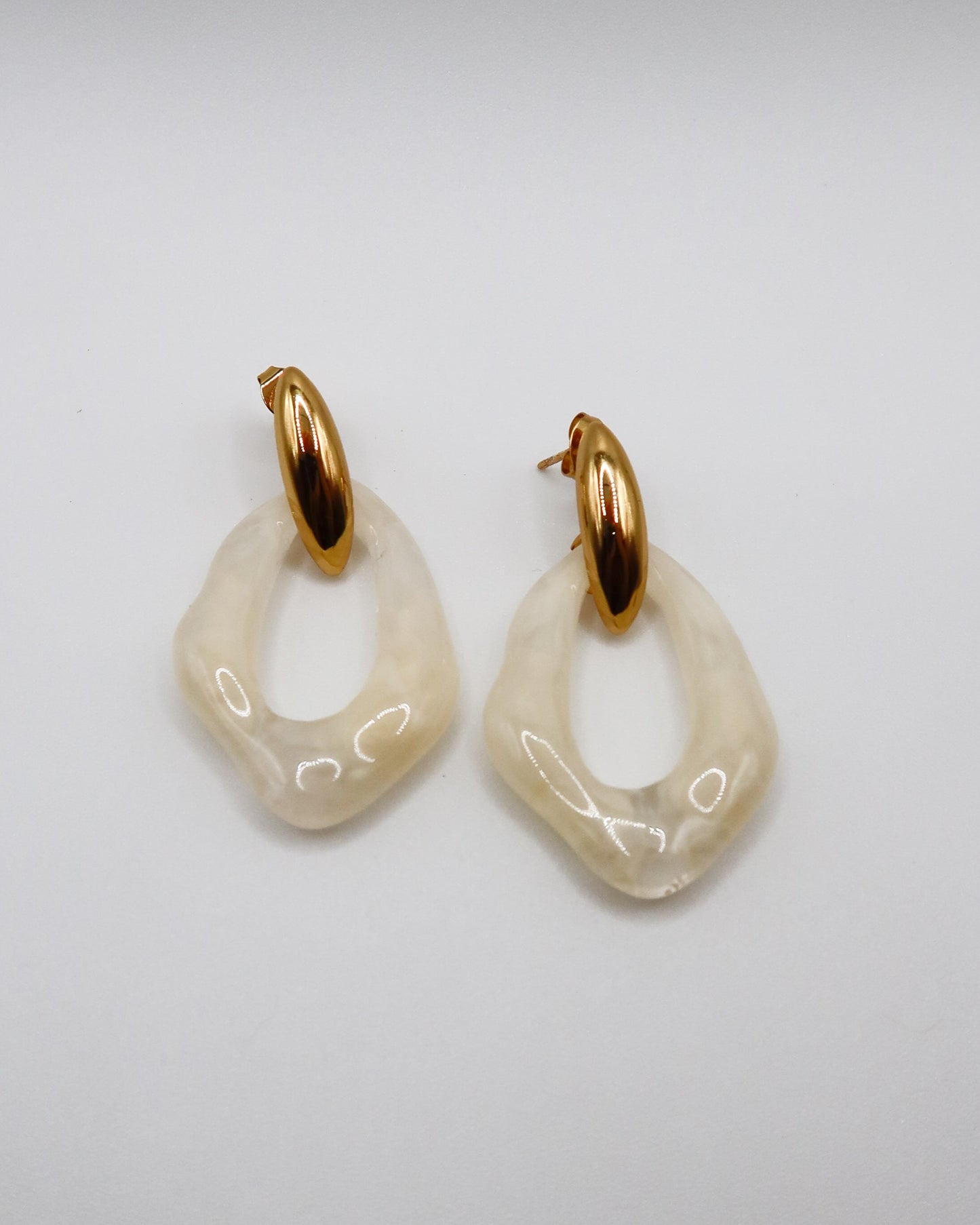 Pair of gold and beige hoop earrings on a light gray background