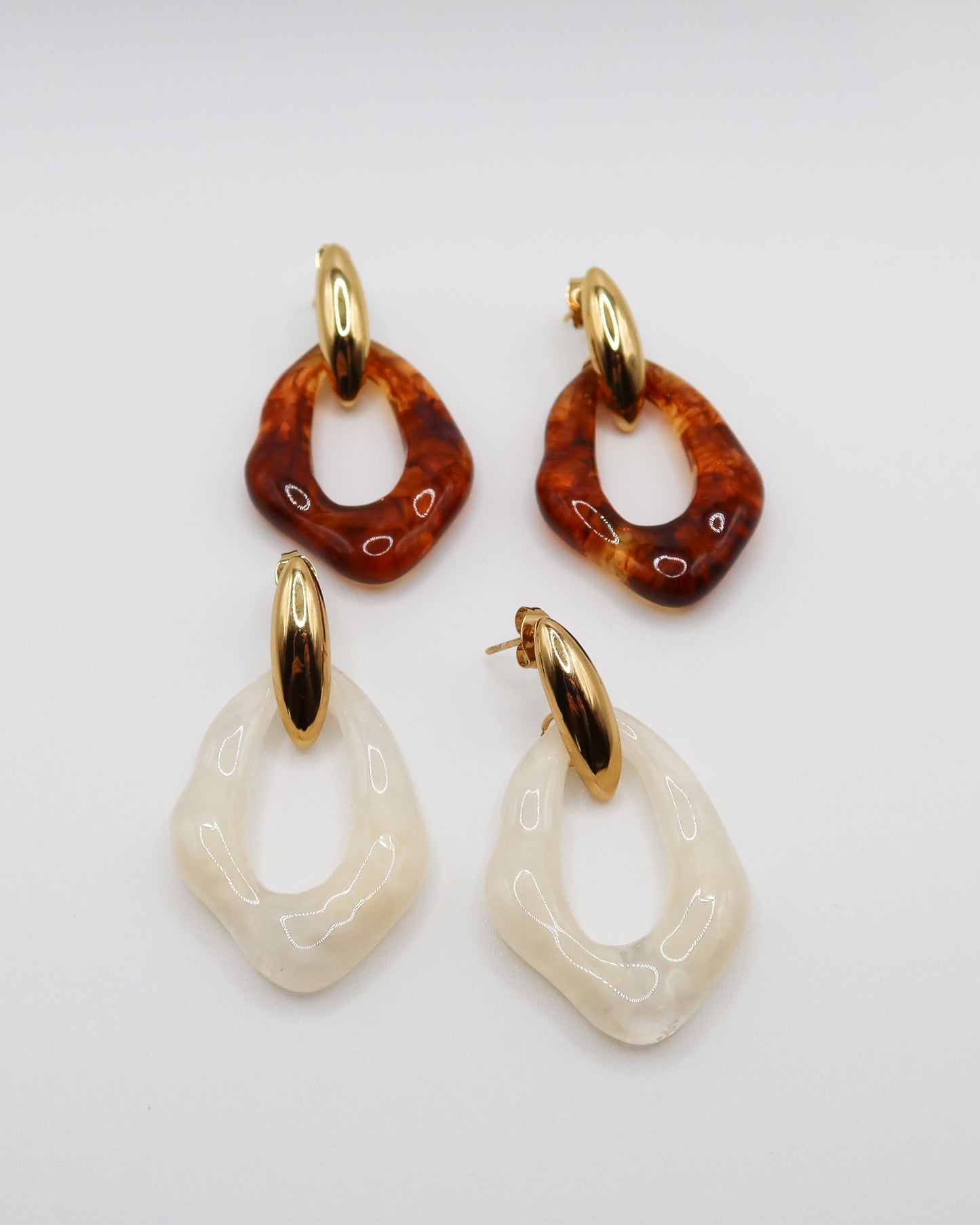 Pair of earrings with amber and white designs on a light gray background