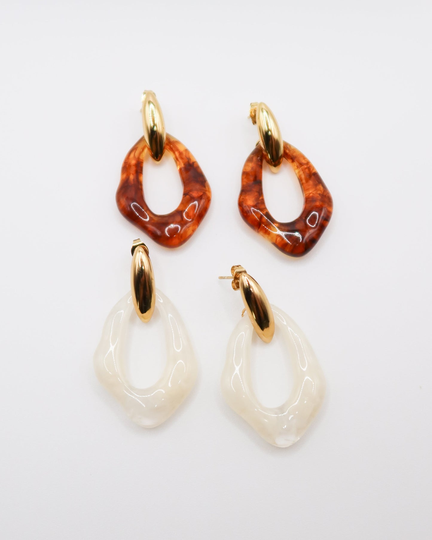 Pair of earrings with amber and white designs on a light gray background