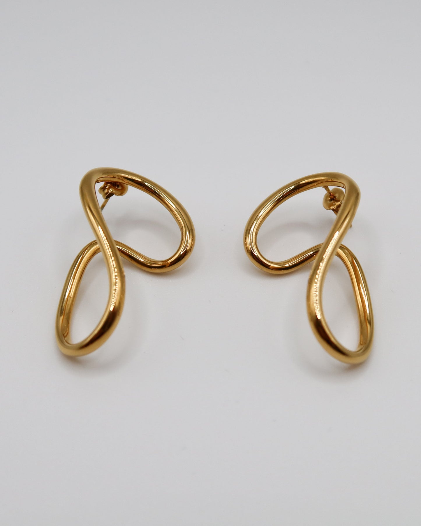 Pair of gold earrings on a light gray background
