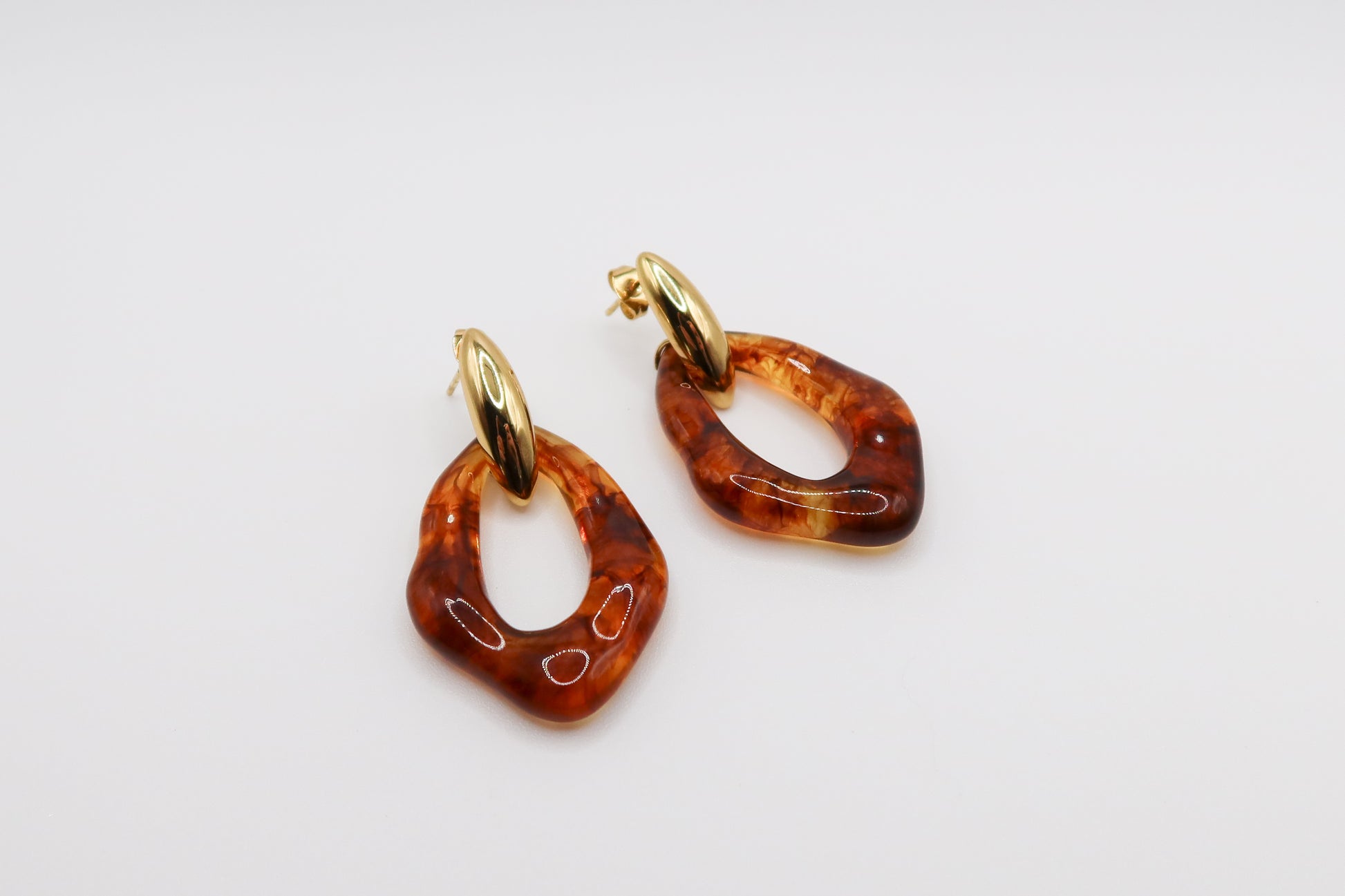 Pair of amber hoop earrings with gold accents on a light gray background