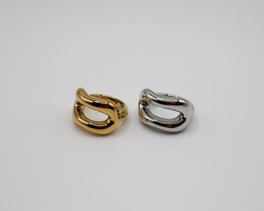 Two gold and silver hoop earrings on a light gray background