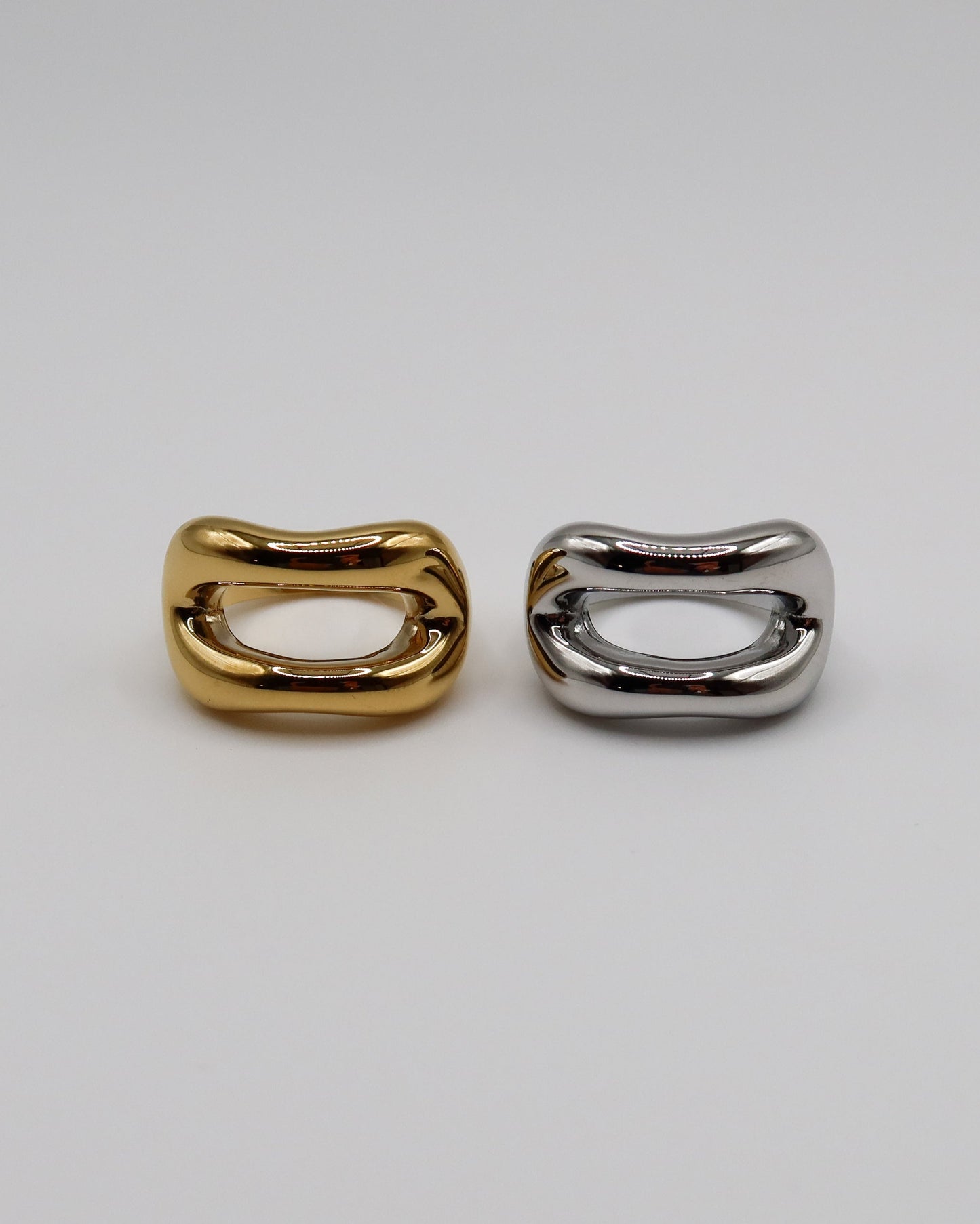 Two metallic rings, one gold and one silver, on a light gray background.