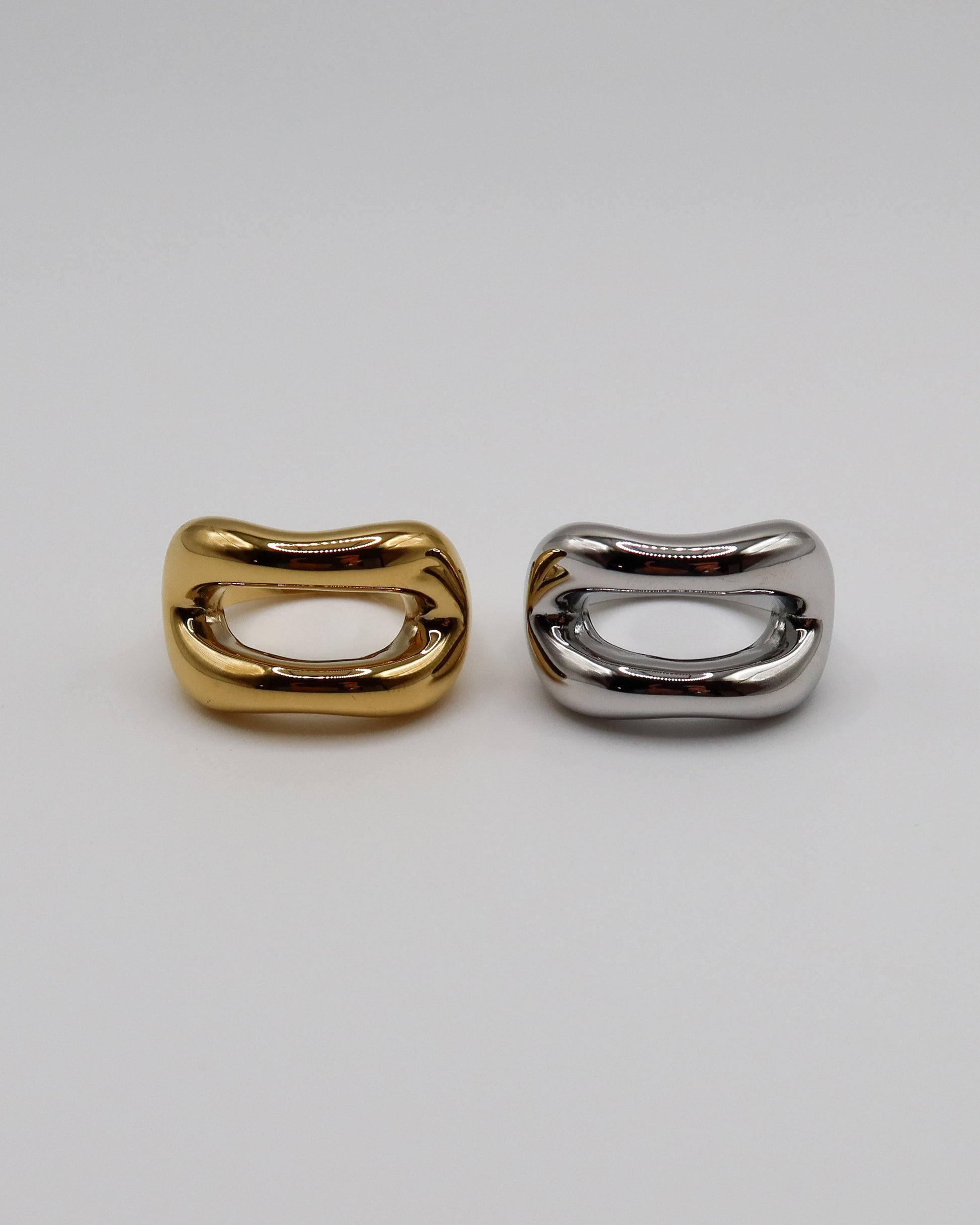 Two metallic rings, one gold and one silver, on a light gray background.