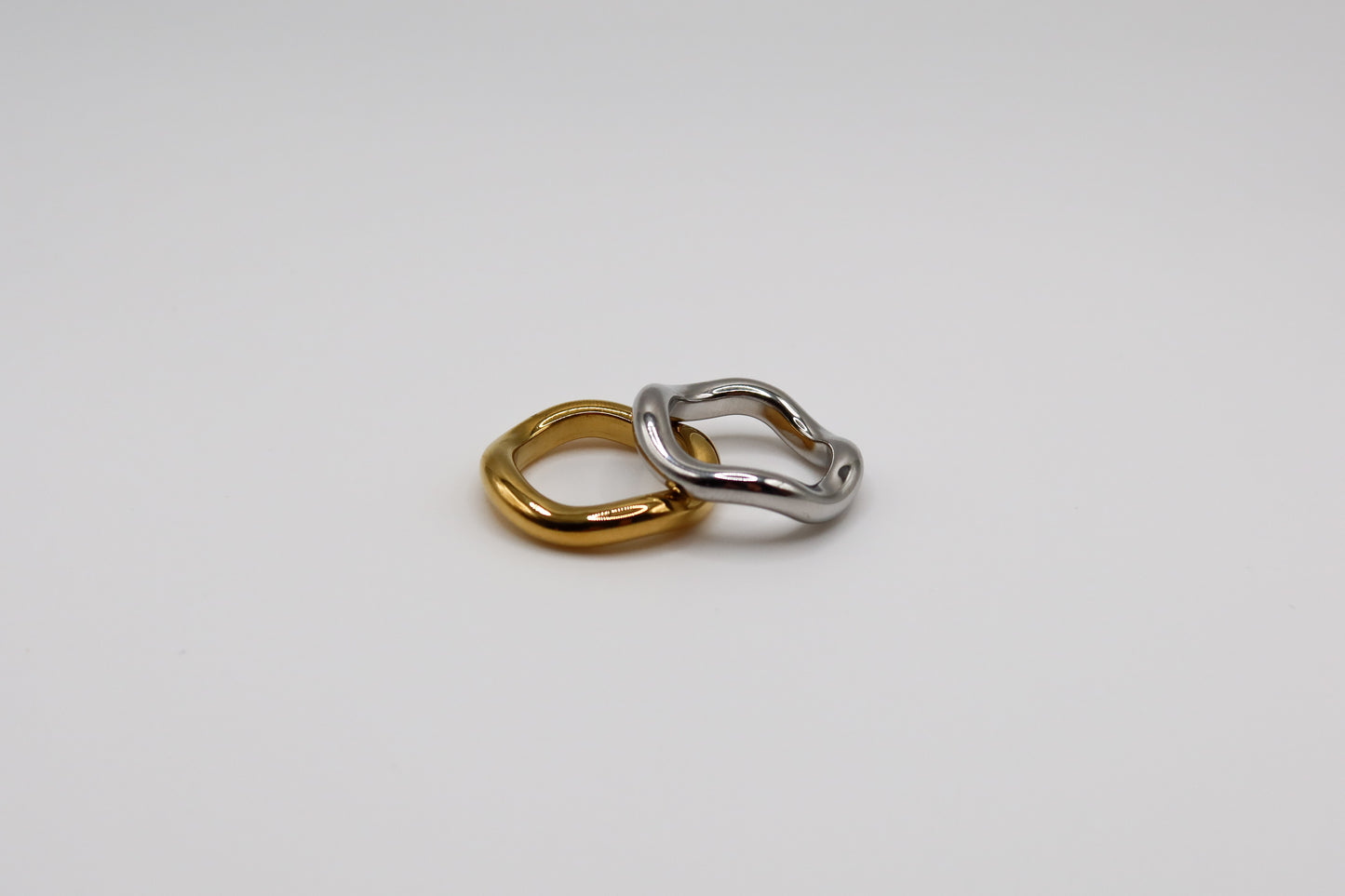 Two interlocking rings, one gold and one silver, on a light gray background.