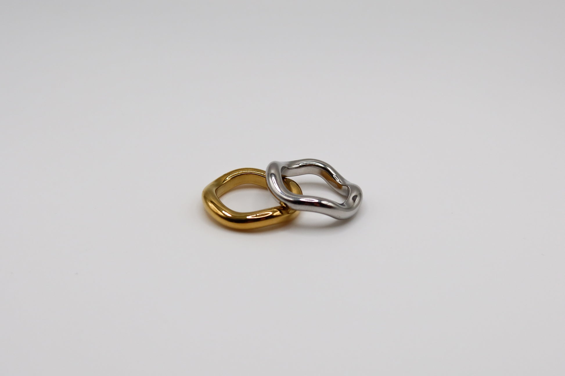 Two interlocking rings, one gold and one silver, on a light gray background.