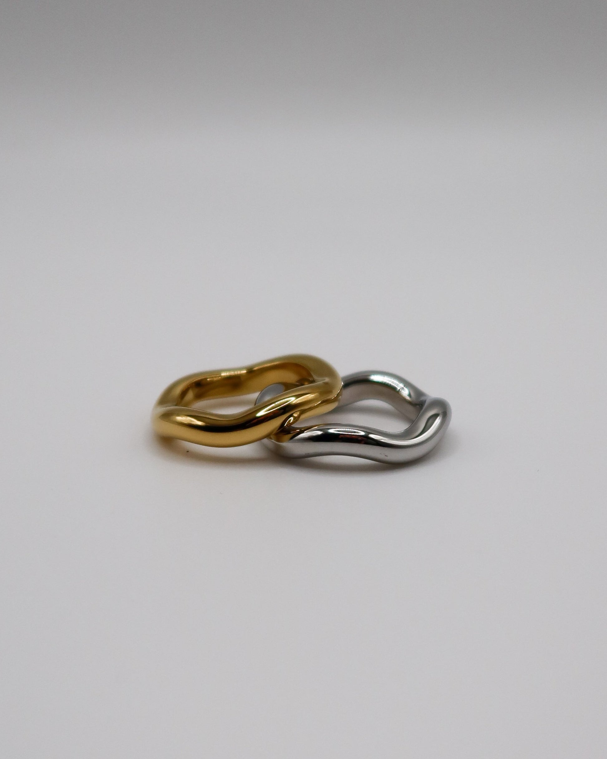 Two gold and silver hoop earrings on a light gray background