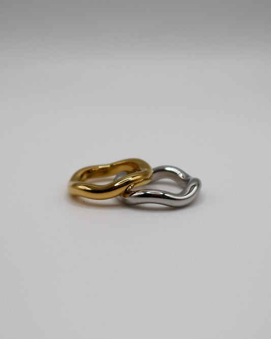 Two gold and silver hoop earrings on a light gray background