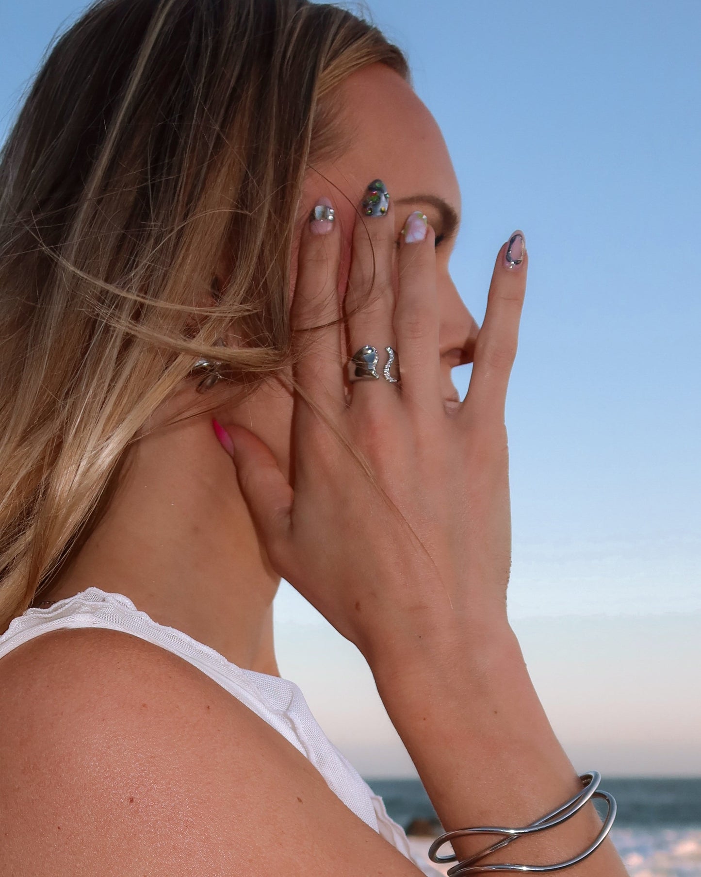 Woman with multiple rings and bracelets on a blurred beach background