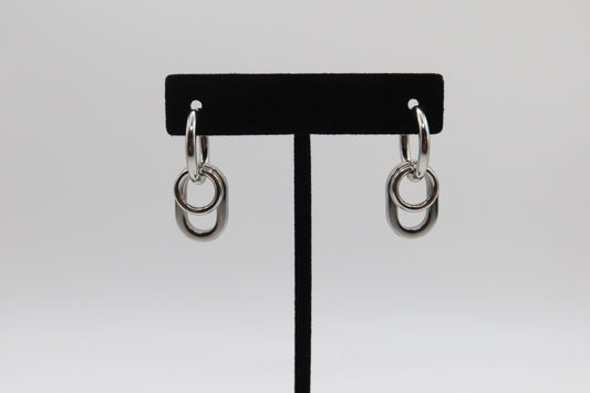Pair of silver hoop earrings on a black earring stand against a white background
