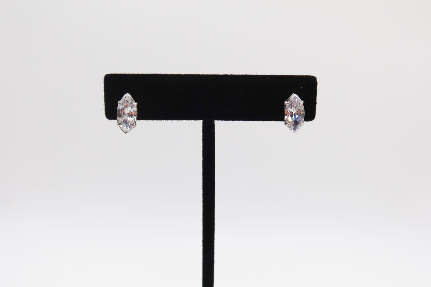 Pair of earrings on a black earring stand against a white background