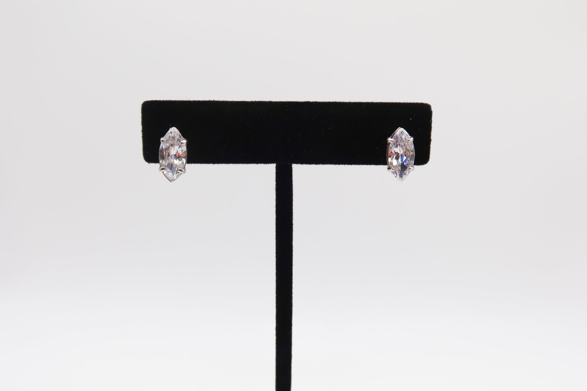 Pair of earrings on a black earring stand against a white background
