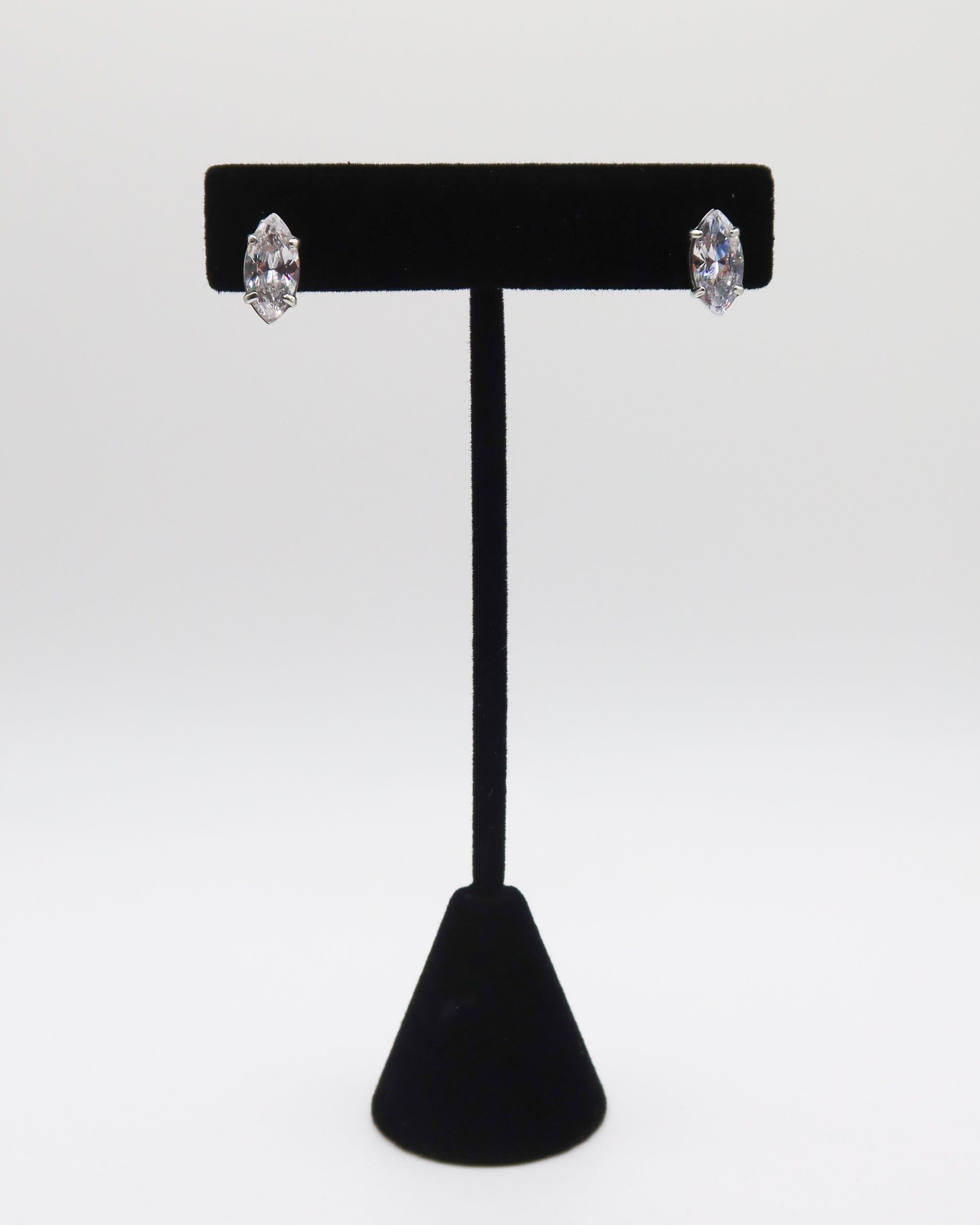 Black T-shaped earring stand with two silver earrings on a white background