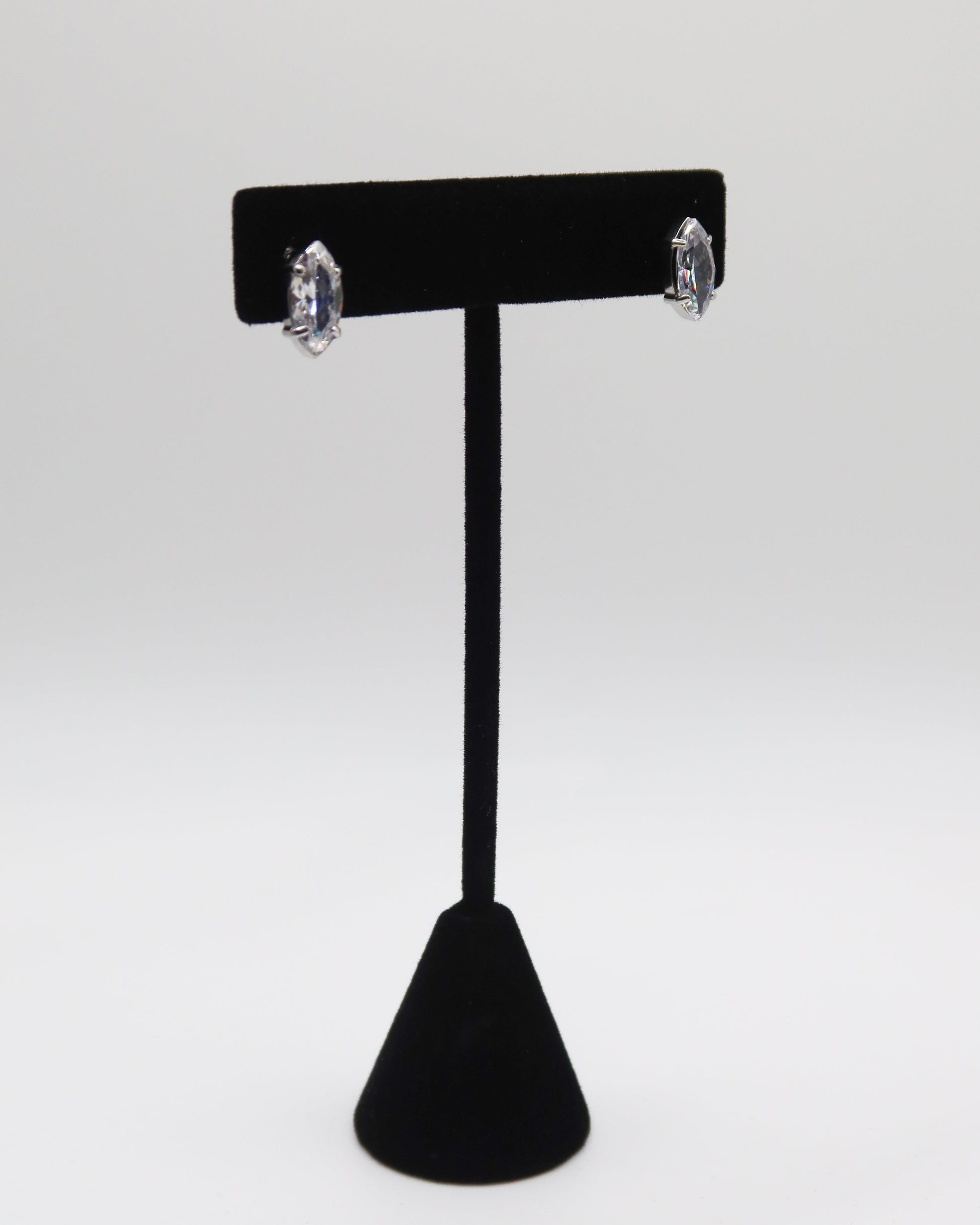 Black earring stand with silver earrings on a white background