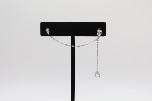 Pair of silver earrings on a black stand against a white background