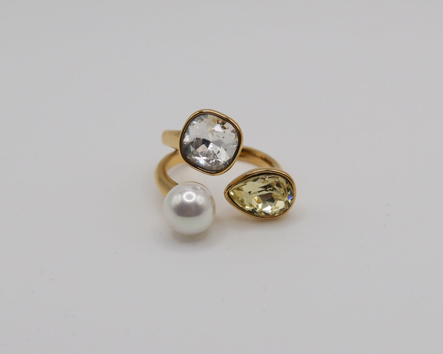 Three gold rings with gemstones on a light gray background
