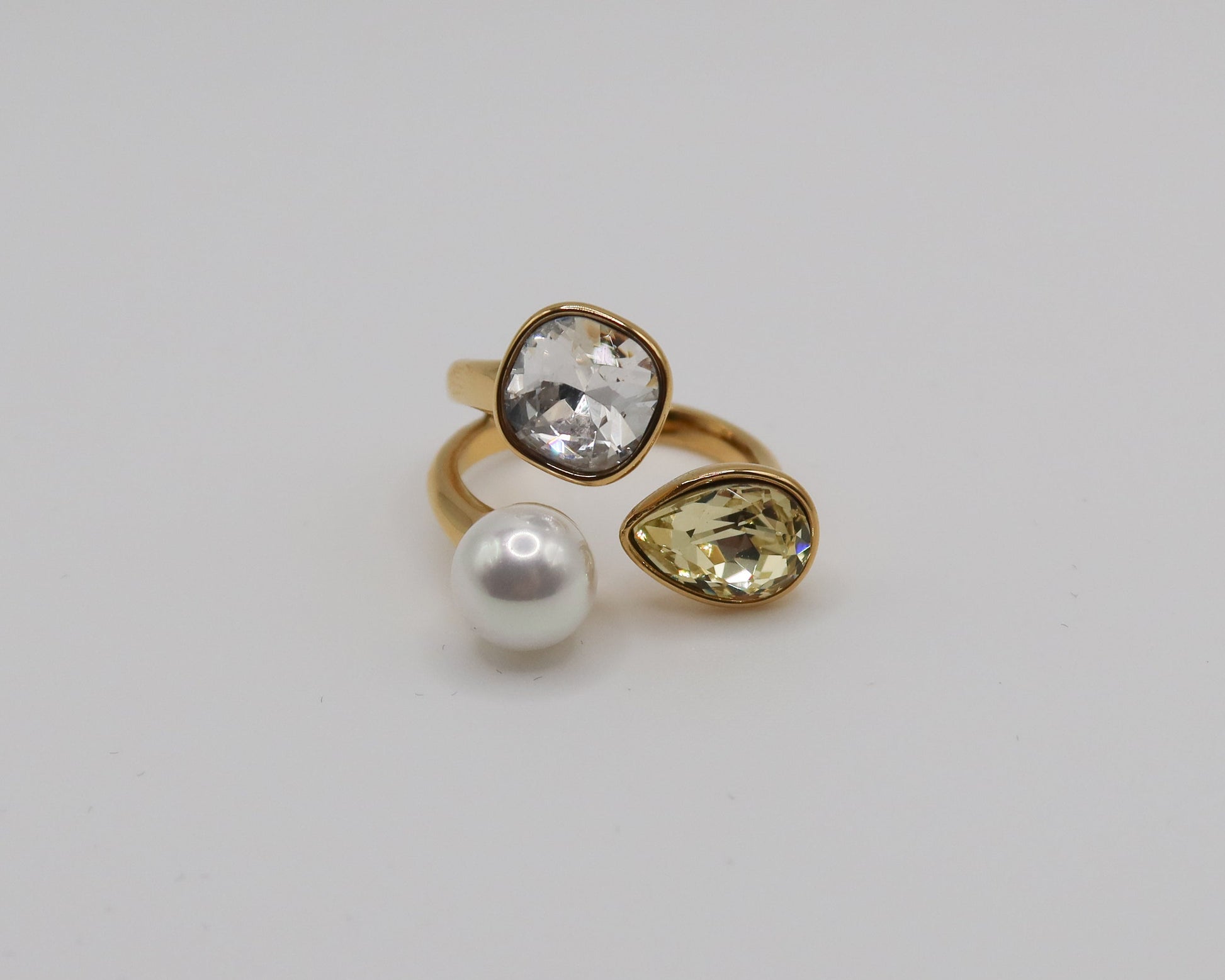 Three gold rings with gemstones on a light gray background