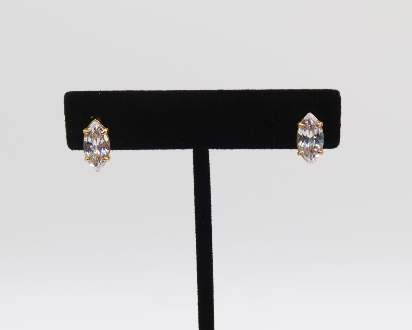 Pair of earrings on a black earring stand against a light gray background
