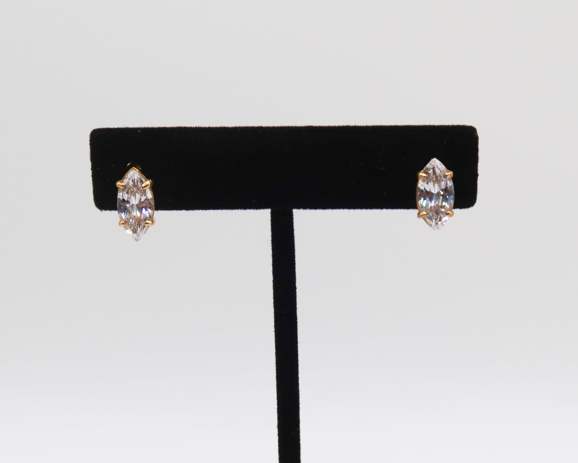 Pair of earrings on a black earring stand against a light gray background