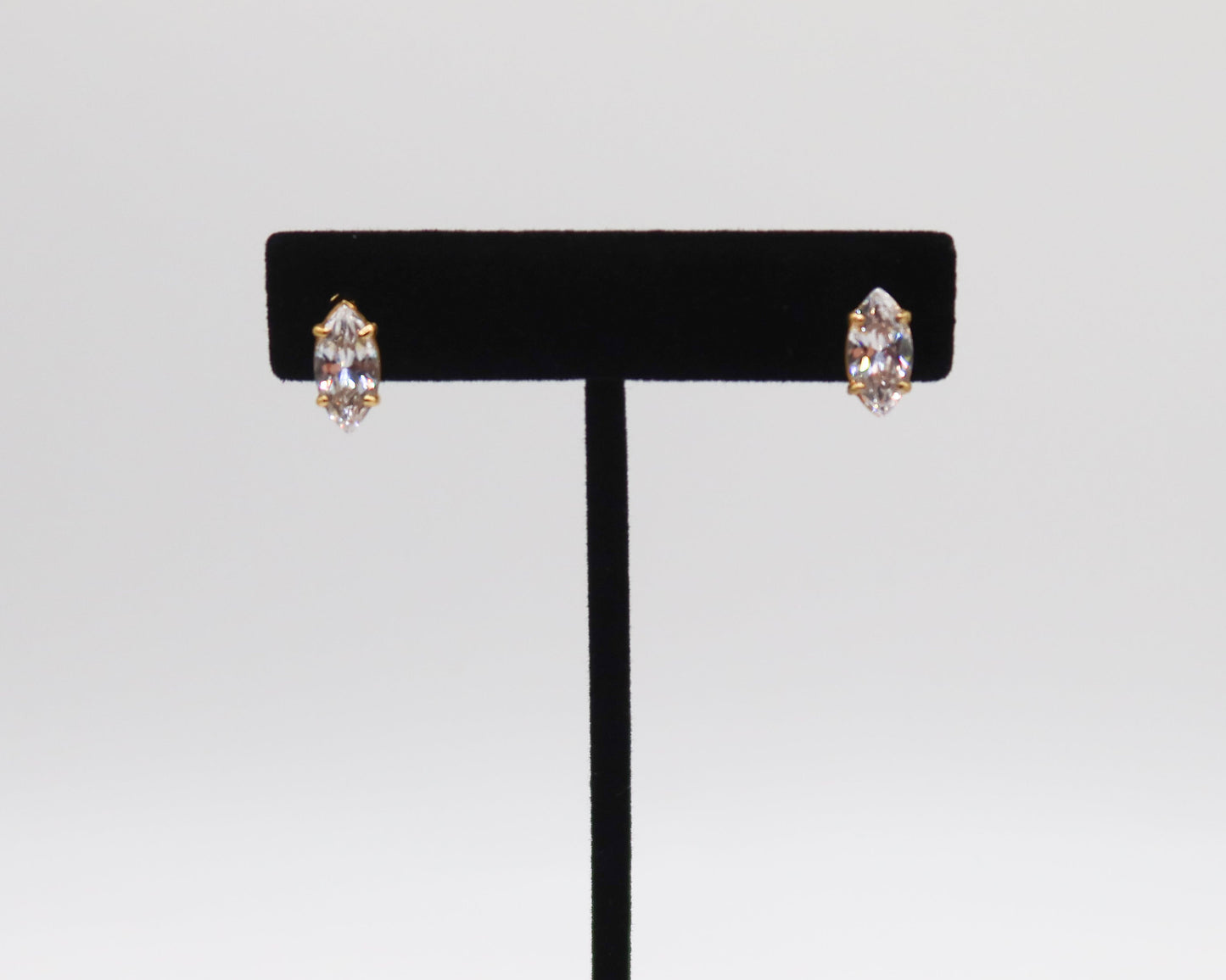 Pair of earrings on a black earring stand against a light gray background