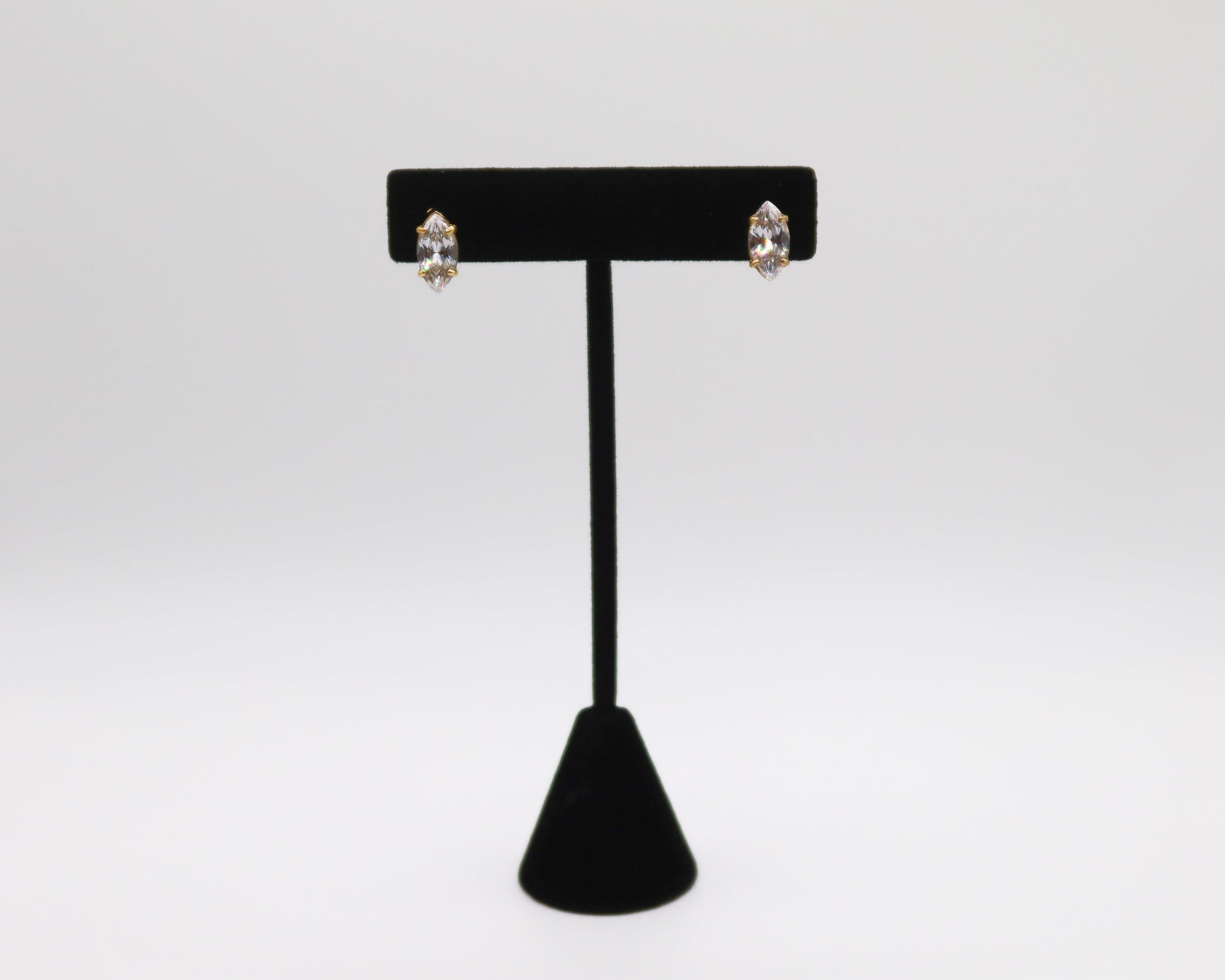 Black earring stand with two earrings on a white background