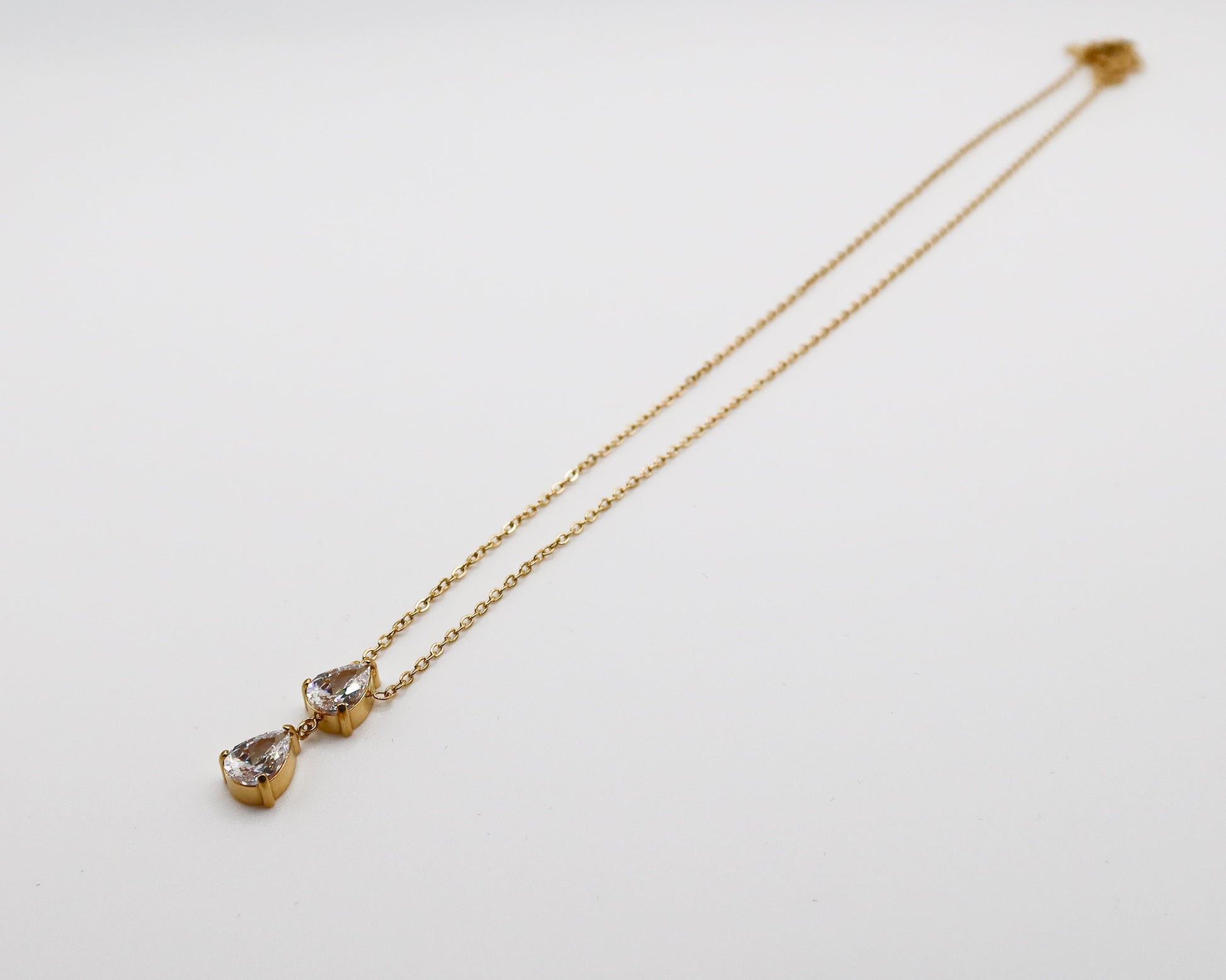 Gold necklace with teardrop-shaped pendants on a light gray background