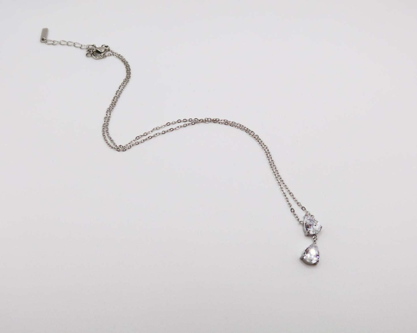 Silver necklace with a heart-shaped pendant on a light gray background
