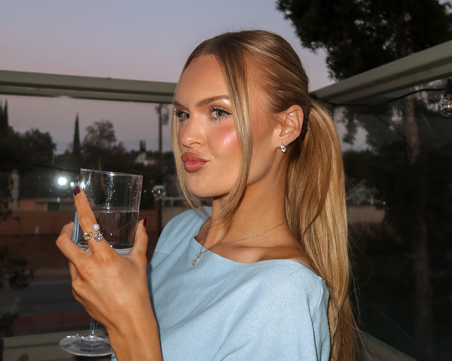 Woman holding a glass of water outdoors at dusk